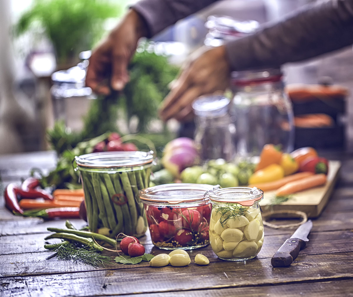 Preserving organic vegetables in jars like grean beans, garlic, carrots, cucumbers, tomatoes, chilis, paprika and radishes.